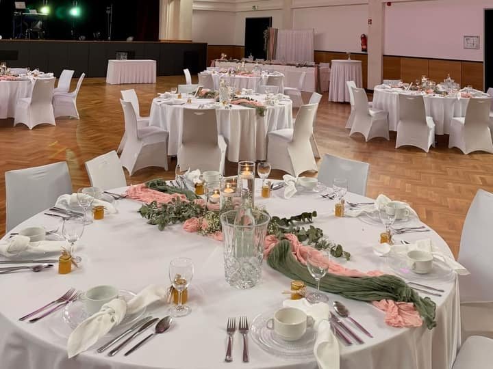 Hochzeitssaal mit rosa Beleuchtung und Rundtischen